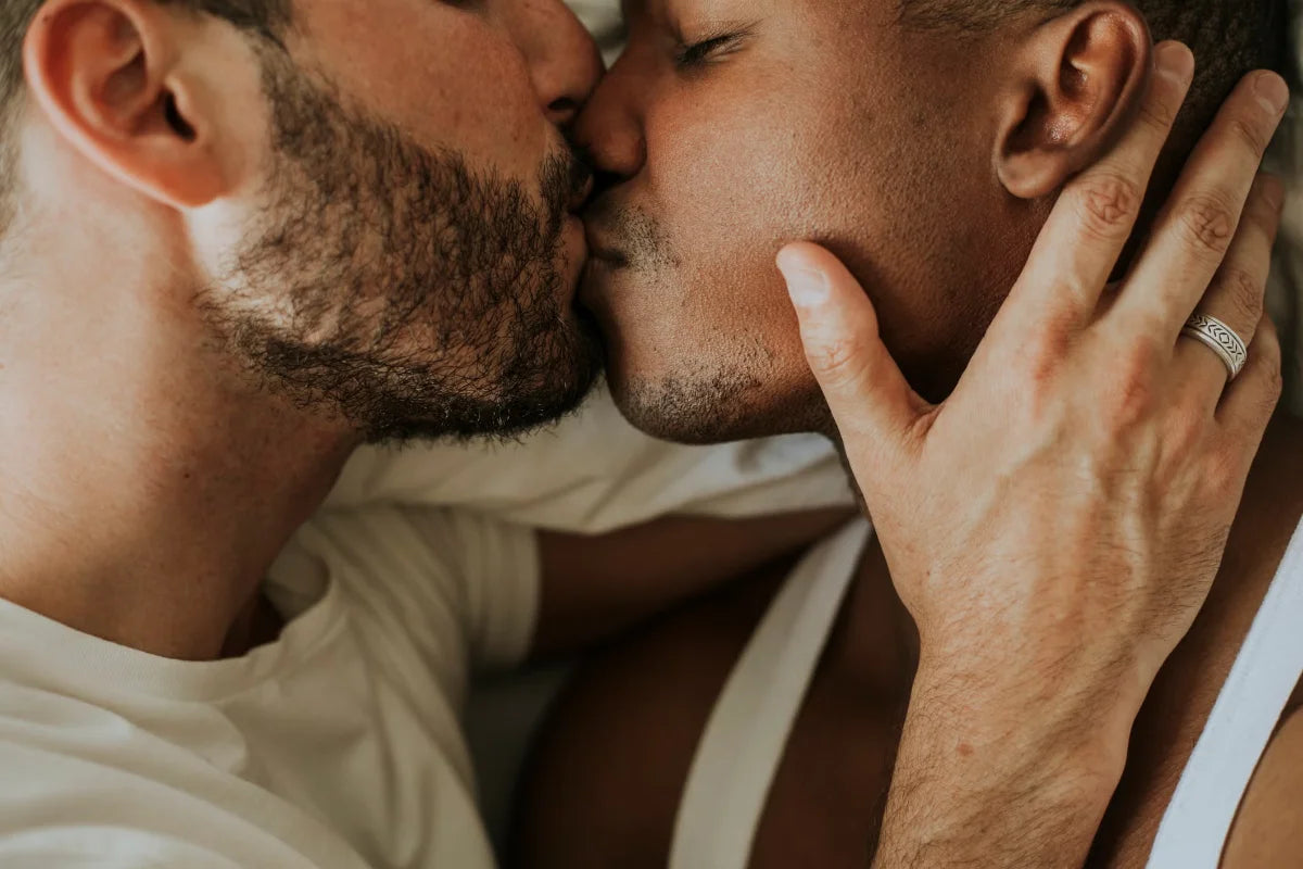 Two people kissing with one person wearing a ring on their finger.