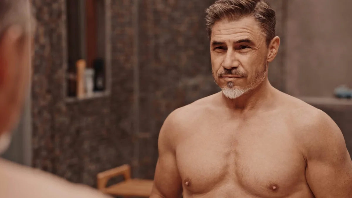 a shirtless older man looking in the mirror